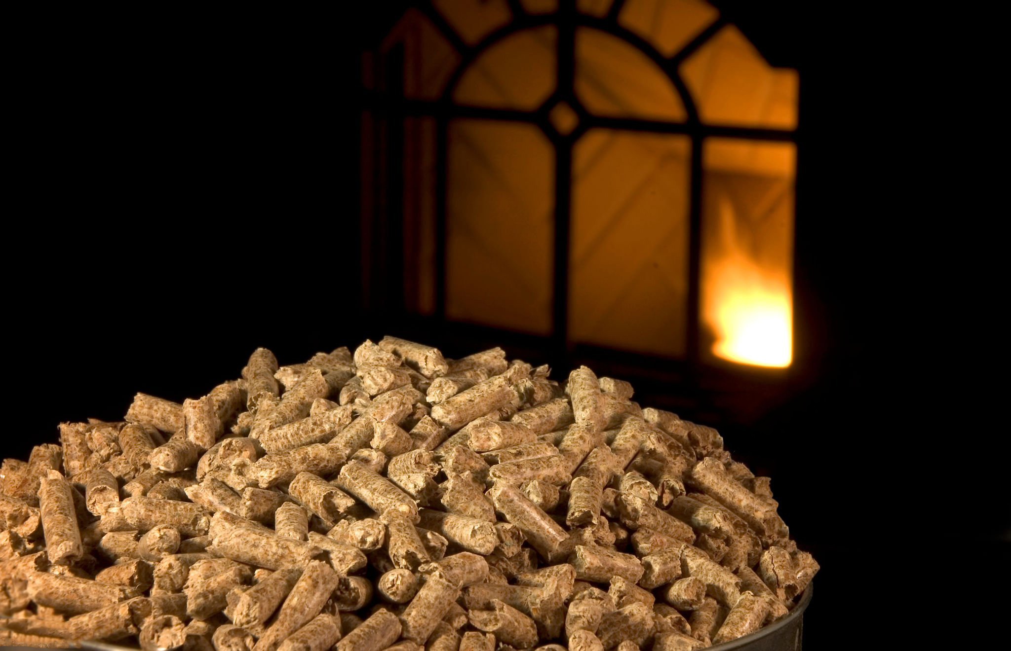 Wood pellets with pellet stove lit in background.